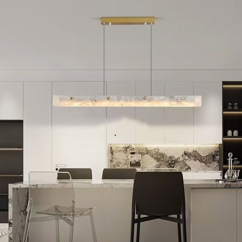 Linea Brass Linear Pendant — brass linear pendant with glass globes hanging over a dining table