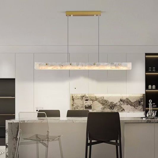 Linea Brass Linear Pendant — brass linear pendant with glass globes hanging over a dining table