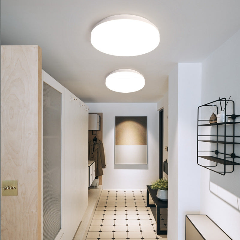 Pura Flush Mount Ceiling Light — round white flush mount ceiling light glowing in a bright hallway